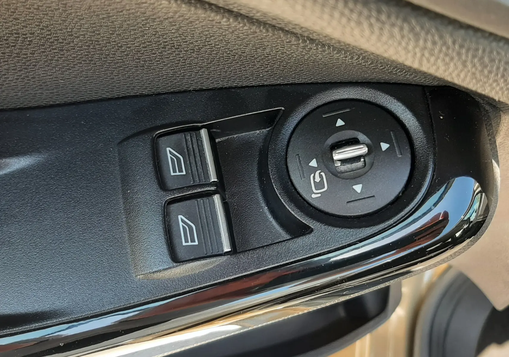 Gros plan sur les commandes de réglage des rétroviseurs et des vitres côté conducteur d'une Ford Fiesta marron métal 2013.