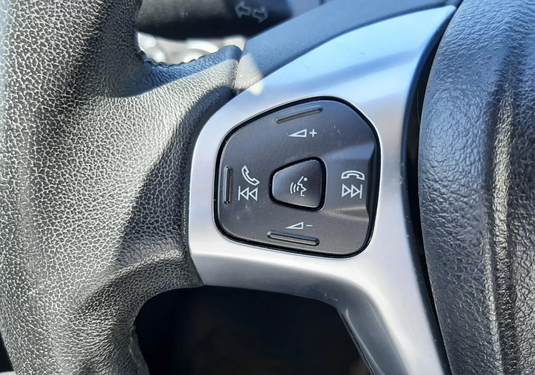 Gros plan sur les commandes multifonctions du volant noir d'une Ford Fiesta marron métal, version Titanium 2013.
