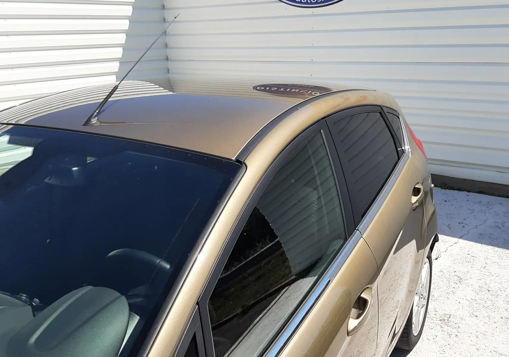 Vue 3/4 avant droit d'une Ford Fiesta marron métal 5 portes avec vitres teintées, garée devant un mur blanc.