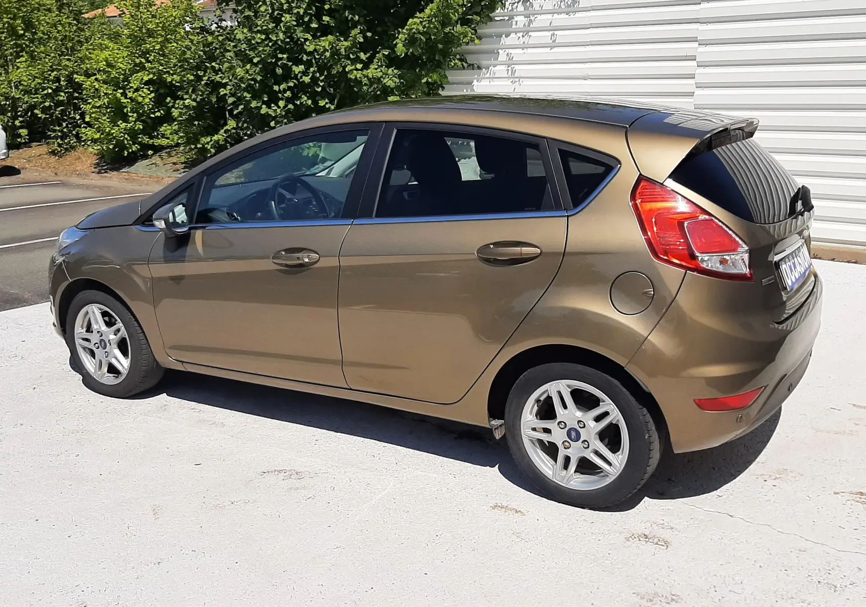 Vue latérale droite d'une Ford Fiesta marron métal 5 portes de 2013, avec jantes alliage et vitres teintées.