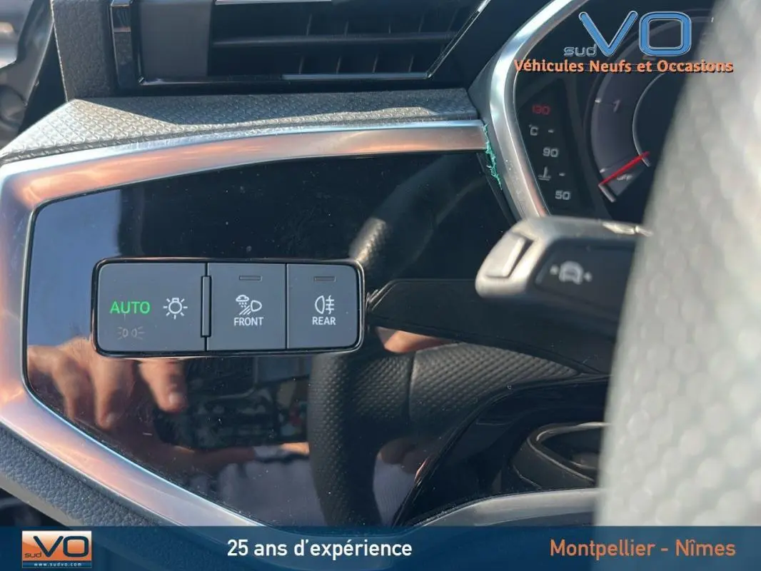 Gros plan sur les commandes d'éclairage automatiques à gauche du volant d'un Audi Q3 Sportback noir S line 2020.