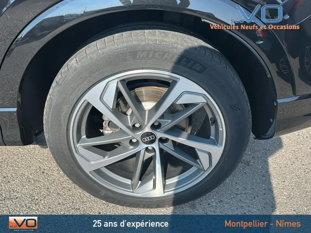 Gros plan sur la roue avant droite de l'Audi Q3 Sportback noir, mettant en valeur la jante S line et le pneu Michelin.