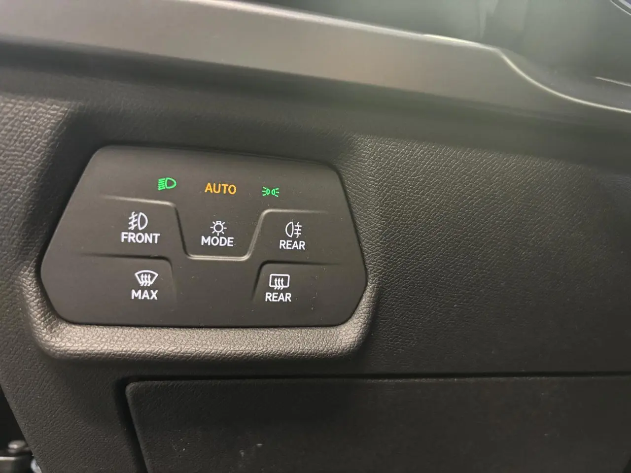 Panneau de commandes d'éclairage intérieur noir avec indicateurs verts et orange, vue rapprochée côté gauche du tableau de bord.