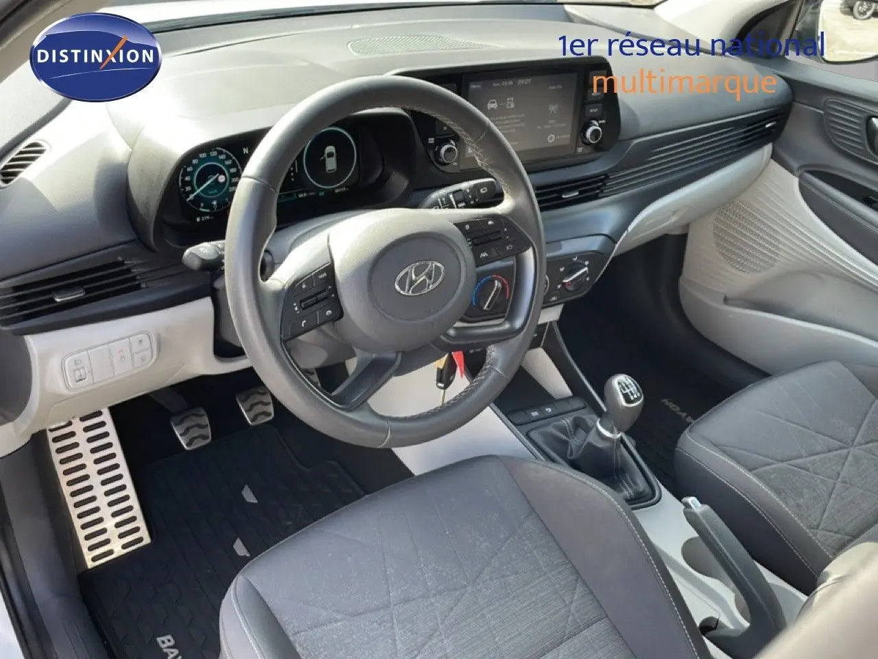 Vue intérieure côté conducteur du Hyundai Bayon blanc polaire 2022, volant cuir multifonction et boîte manuelle visible.