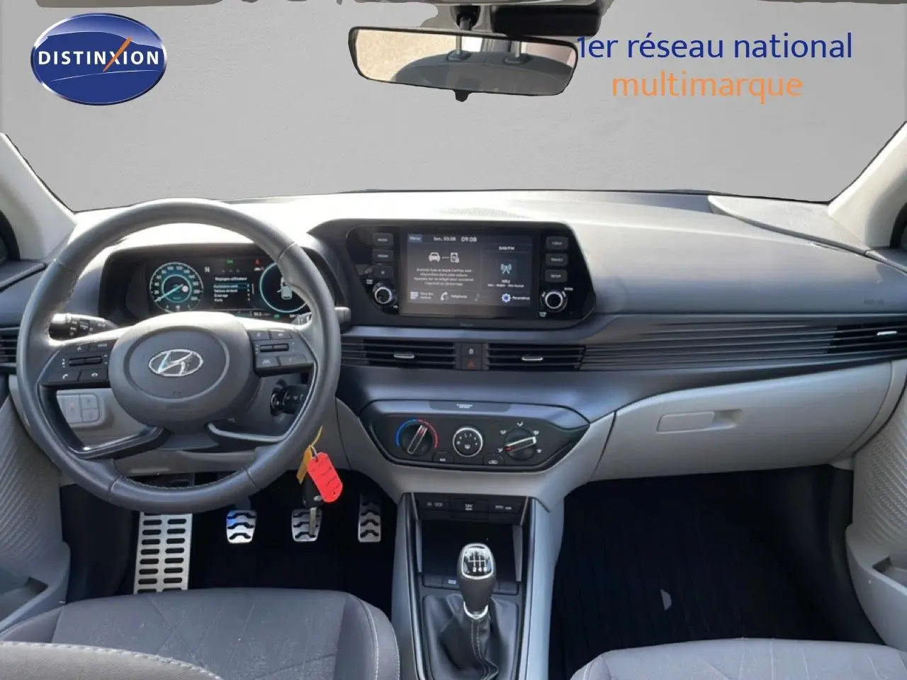 Vue intérieure avant du Hyundai Bayon blanc polaire 2022, avec tableau de bord numérique et volant cuir multifonction.