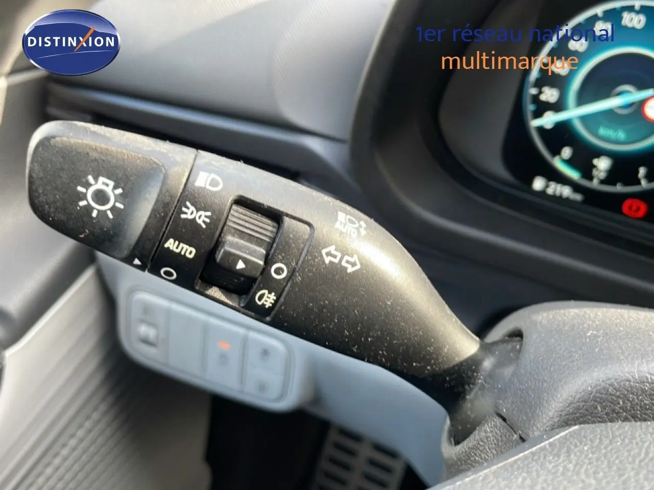 Gros plan sur la commande des feux et clignotants à gauche du volant dans l’habitacle gris noir du Hyundai Bayon blanc polaire.