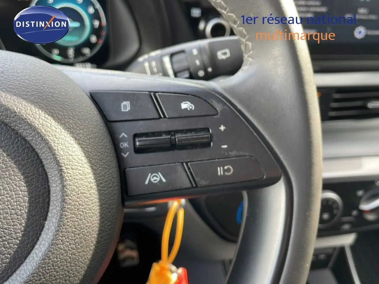 Gros plan sur les commandes au volant côté gauche du Hyundai Bayon blanc polaire, avec tableau de bord en arrière-plan flou.