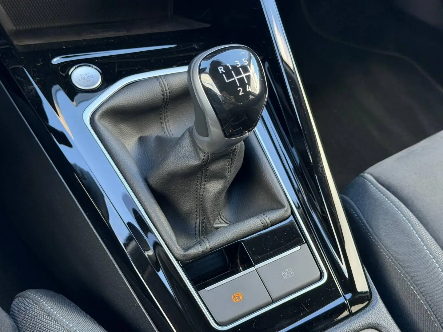 Gros plan sur le levier de vitesses manuel noir et la console brillante d'une Volkswagen Golf 2024 gris lunaire.