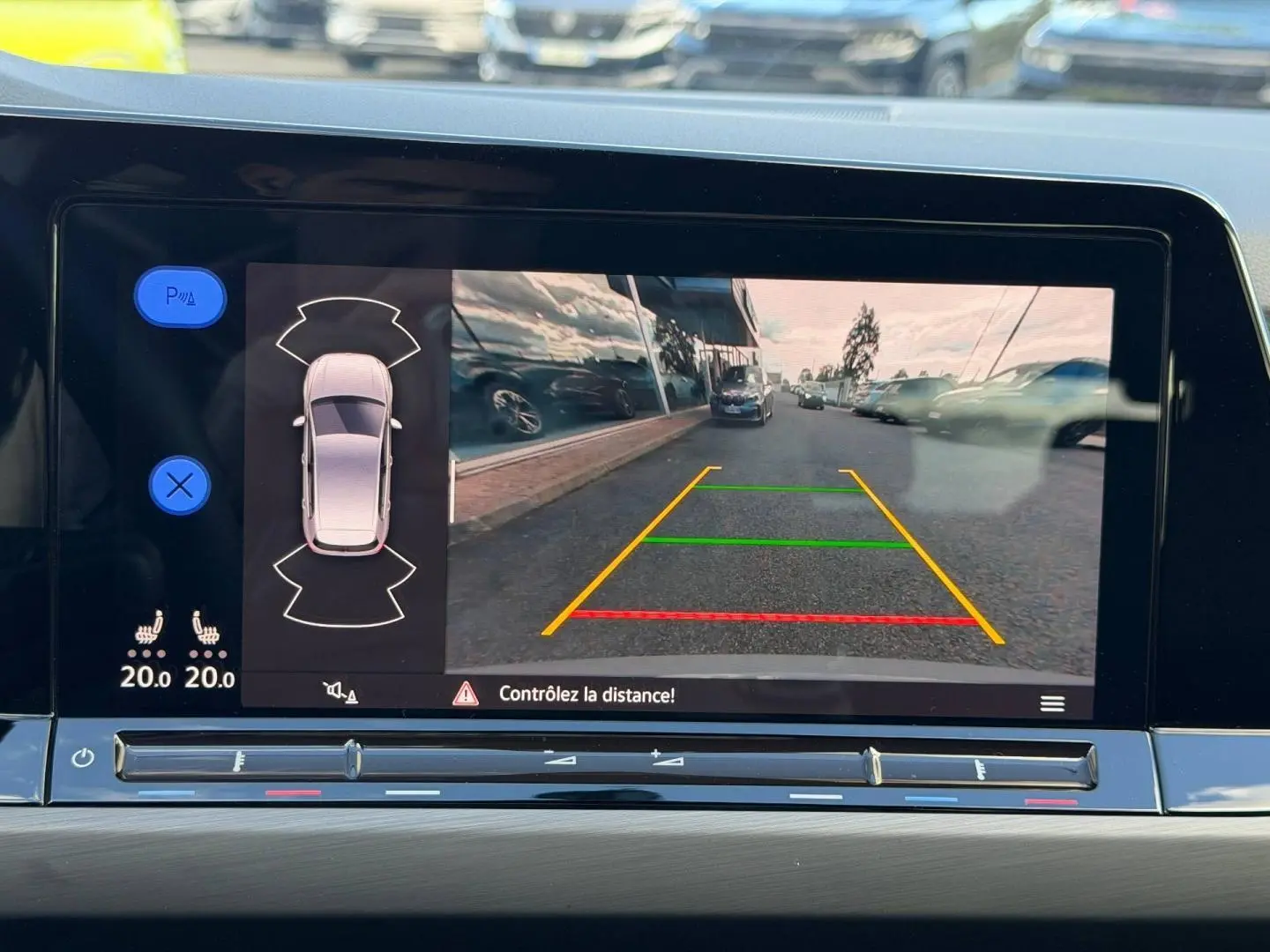 Écran tactile intérieur montrant la caméra de recul et l’aide au stationnement d’une Volkswagen Golf gris lunaire.