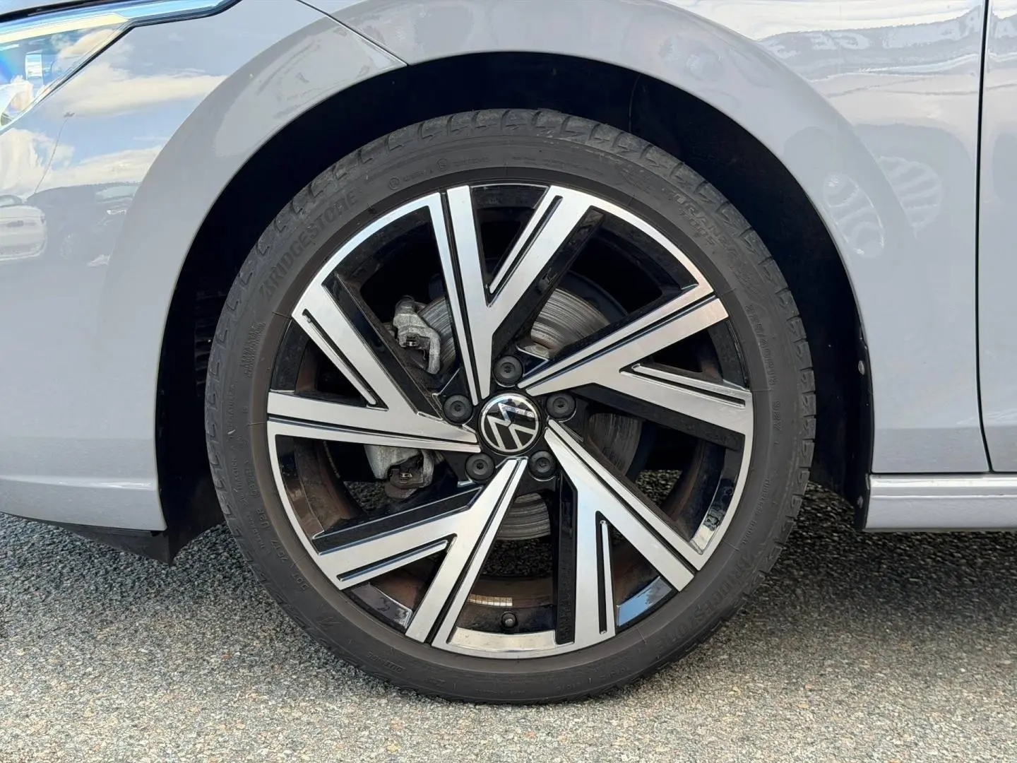 Gros plan sur la roue avant gauche de la Volkswagen Golf 1.5 TSI gris lunaire avec jante alliage noire et argent.