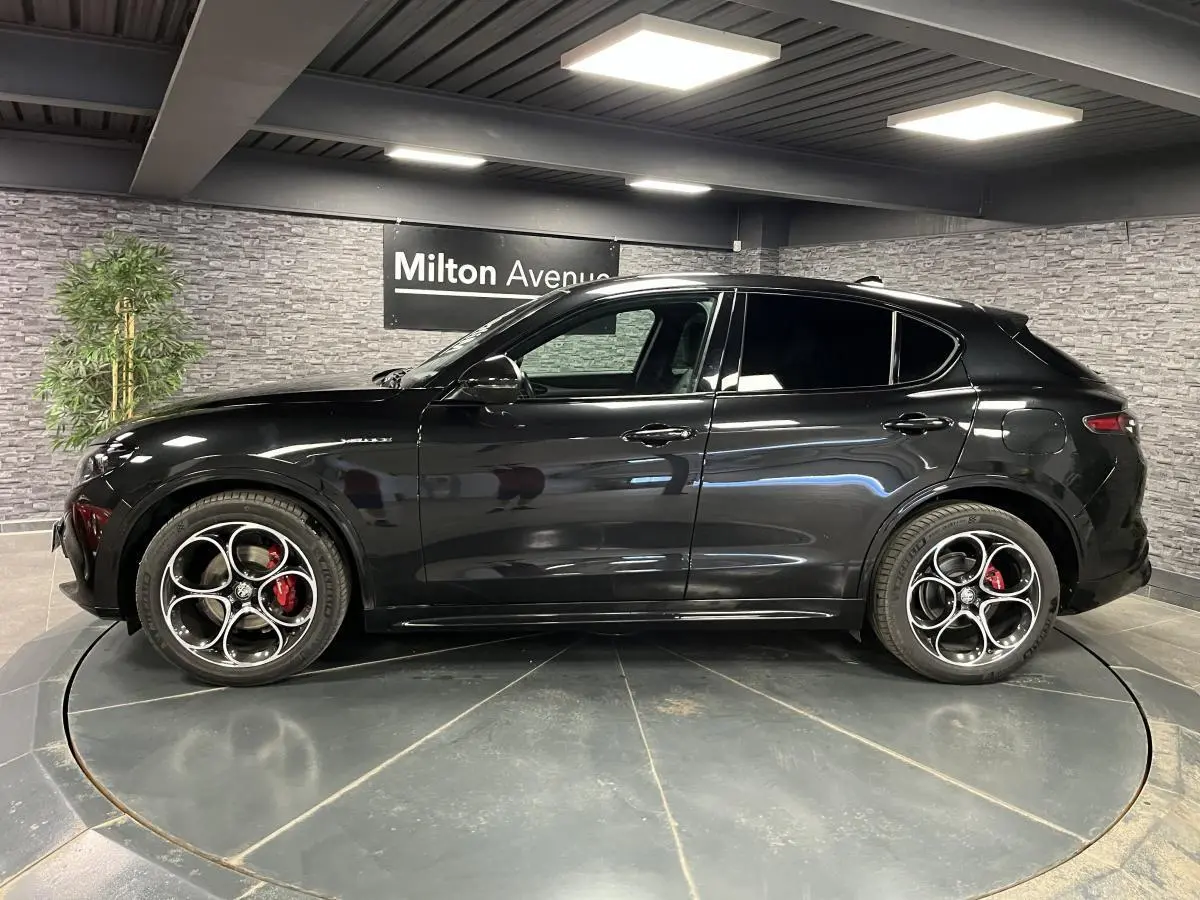 Profil côté gauche d'un Alfa Romeo Stelvio Veloce 2024 noir métallisé avec jantes 20 pouces et étriers rouges Brembo.