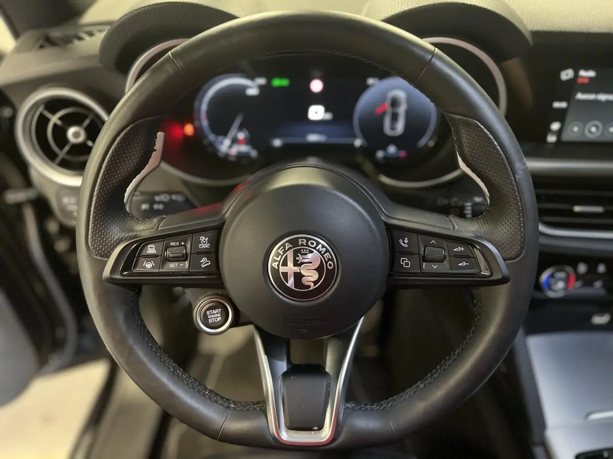 Gros plan sur le volant sport en cuir noir de l'Alfa Romeo Stelvio 2024 avec tableau de bord digital lumineux.