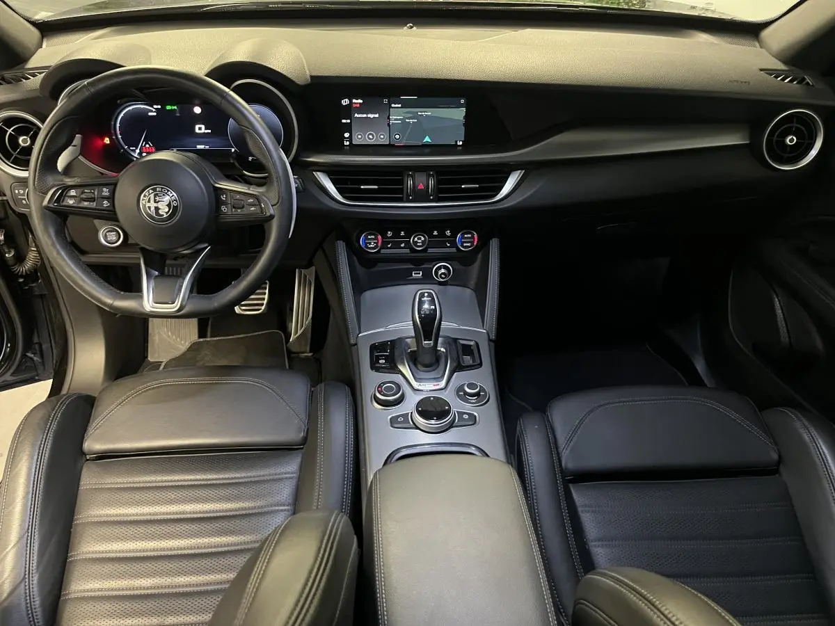 Intérieur noir cuir de l'Alfa Romeo Stelvio Veloce 2024, vue avant sur tableau de bord et console centrale.