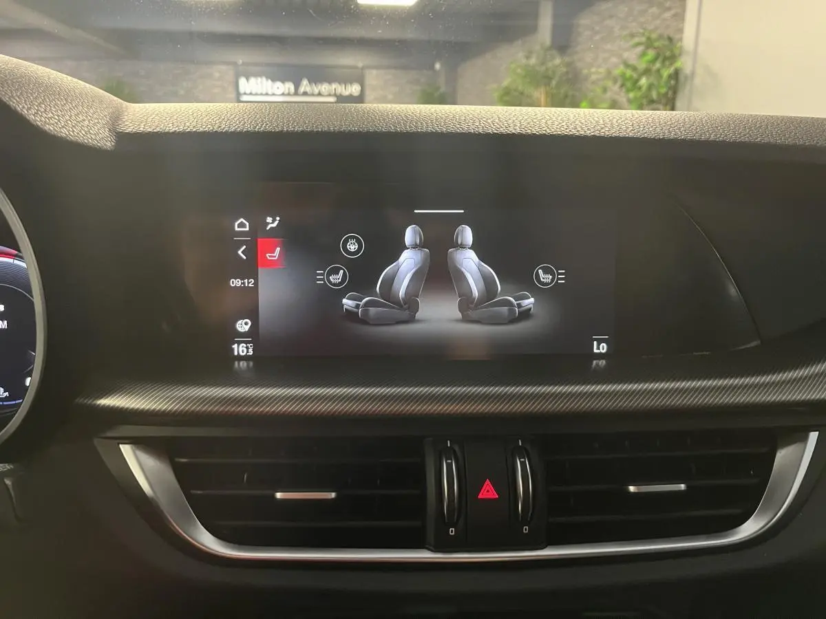 Écran tactile du tableau de bord de l'Alfa Romeo Stelvio 2024 montrant le réglage des sièges chauffants en intérieur noir.