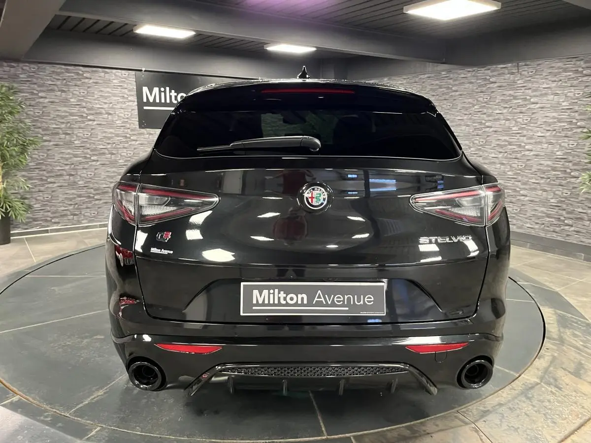 Vue arrière d'un Alfa Romeo Stelvio noir Vulcano avec double sortie d'échappement et badge Veloce visible.