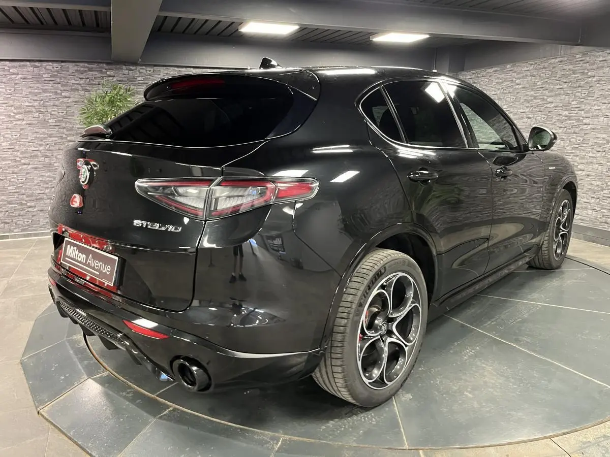 Vue 3/4 arrière droite de l'Alfa Romeo Stelvio noir Vulcano avec jantes 20 pouces et double sortie d'échappement noire.