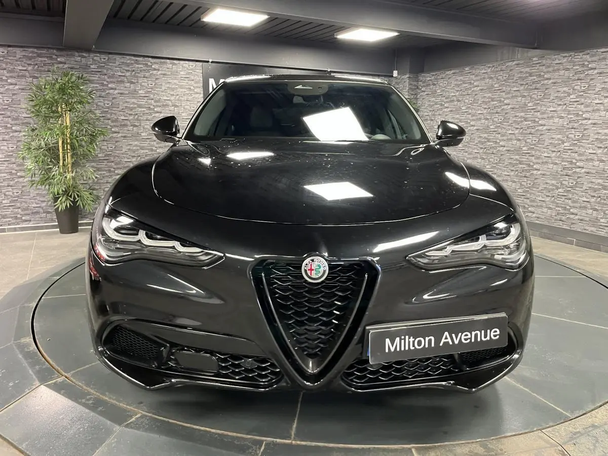 Vue frontale d'un Alfa Romeo Stelvio Veloce noir métallisé avec calandre en V noir et phares LED distinctifs.