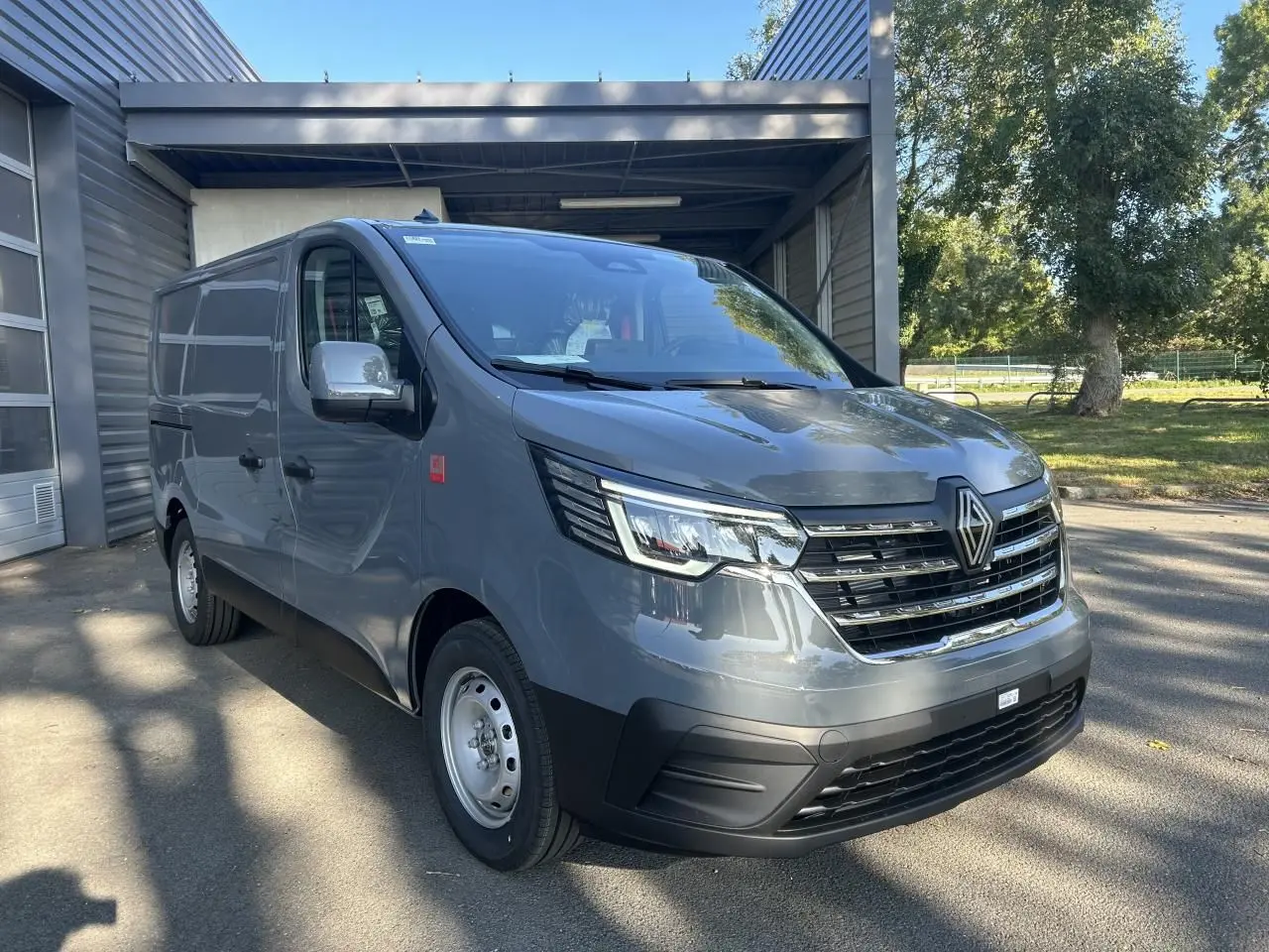 Vue latérale droite d'un Renault Trafic Fourgon gris urbain 2025, avec roues acier et silhouette épurée en showroom.