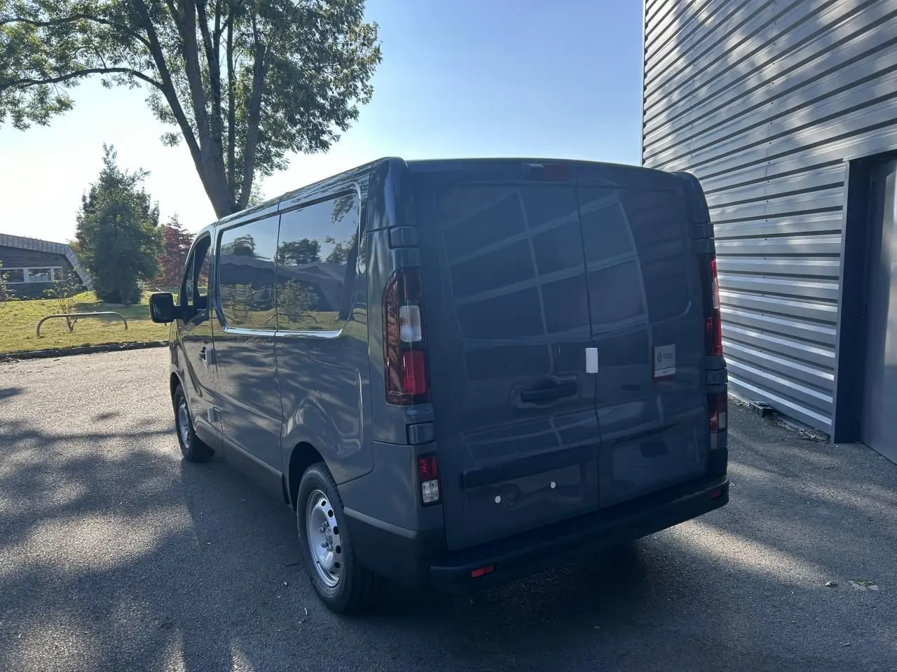 Vue 3/4 arrière droite du Renault Trafic Fourgon L1H1 Gris Urbain avec caméra et radar de recul visibles.