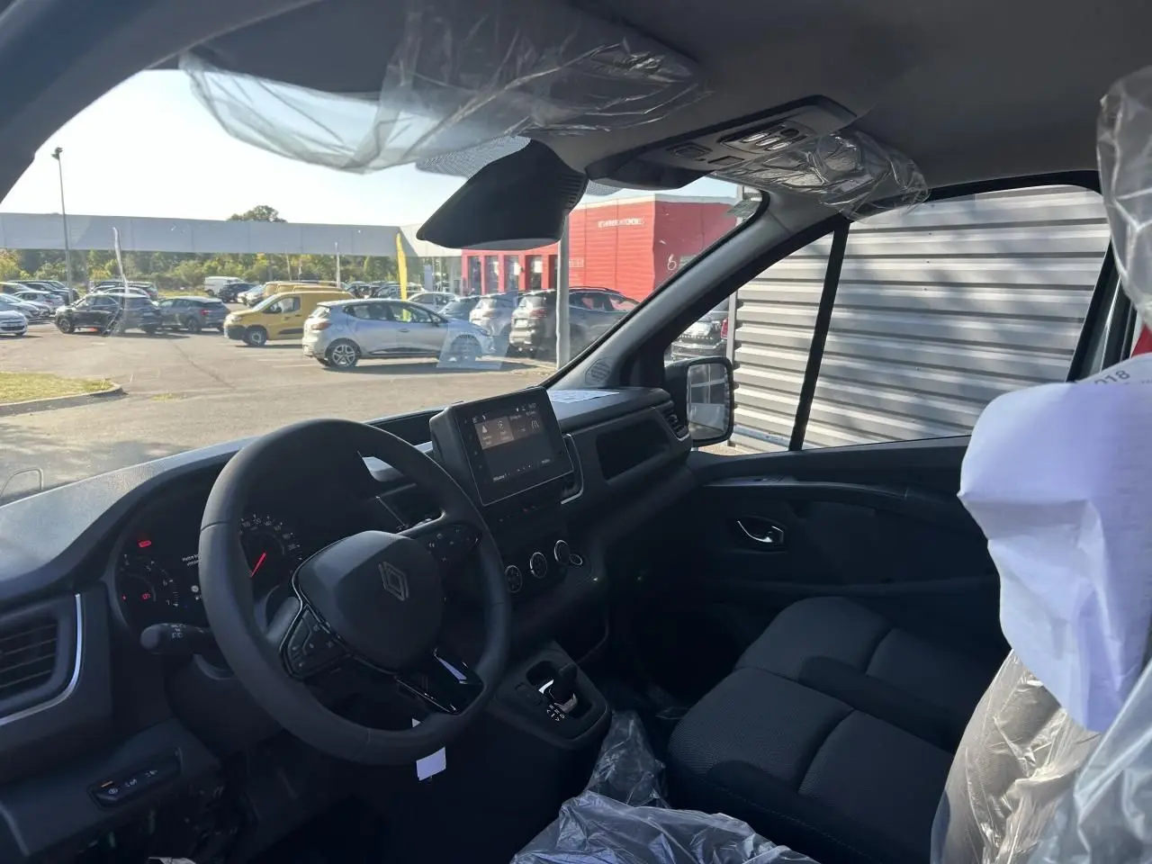 Vue 3/4 arrière droite du Renault Trafic Fourgon gris urbain 2025, avec portes arrière fermées et jantes acier.