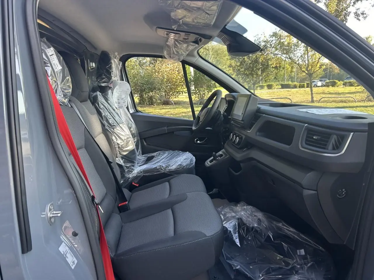 Vue latérale droite du Renault Trafic Fourgon gris urbain 2025, avec roues acier et porte coulissante visible.