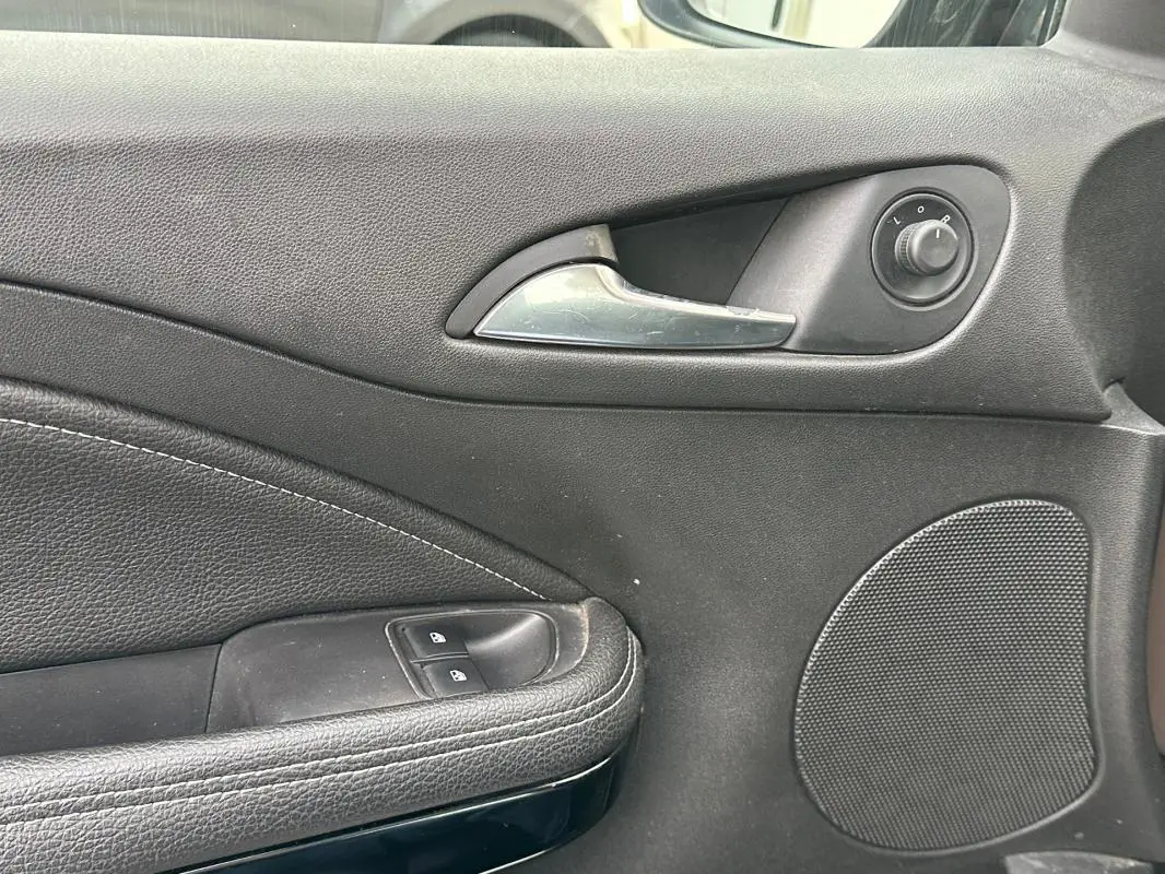 Gros plan sur la poignée intérieure et les commandes de la porte avant gauche de l’Opel Adam marron de 2016.