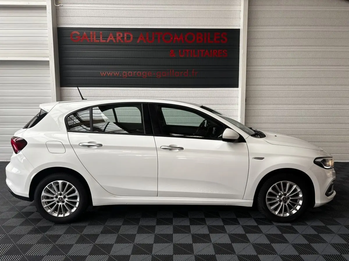 Profil côté droit d'une FIAT TIPO blanche 2021 en intérieur, avec jantes alliage et poignées de porte chromées.