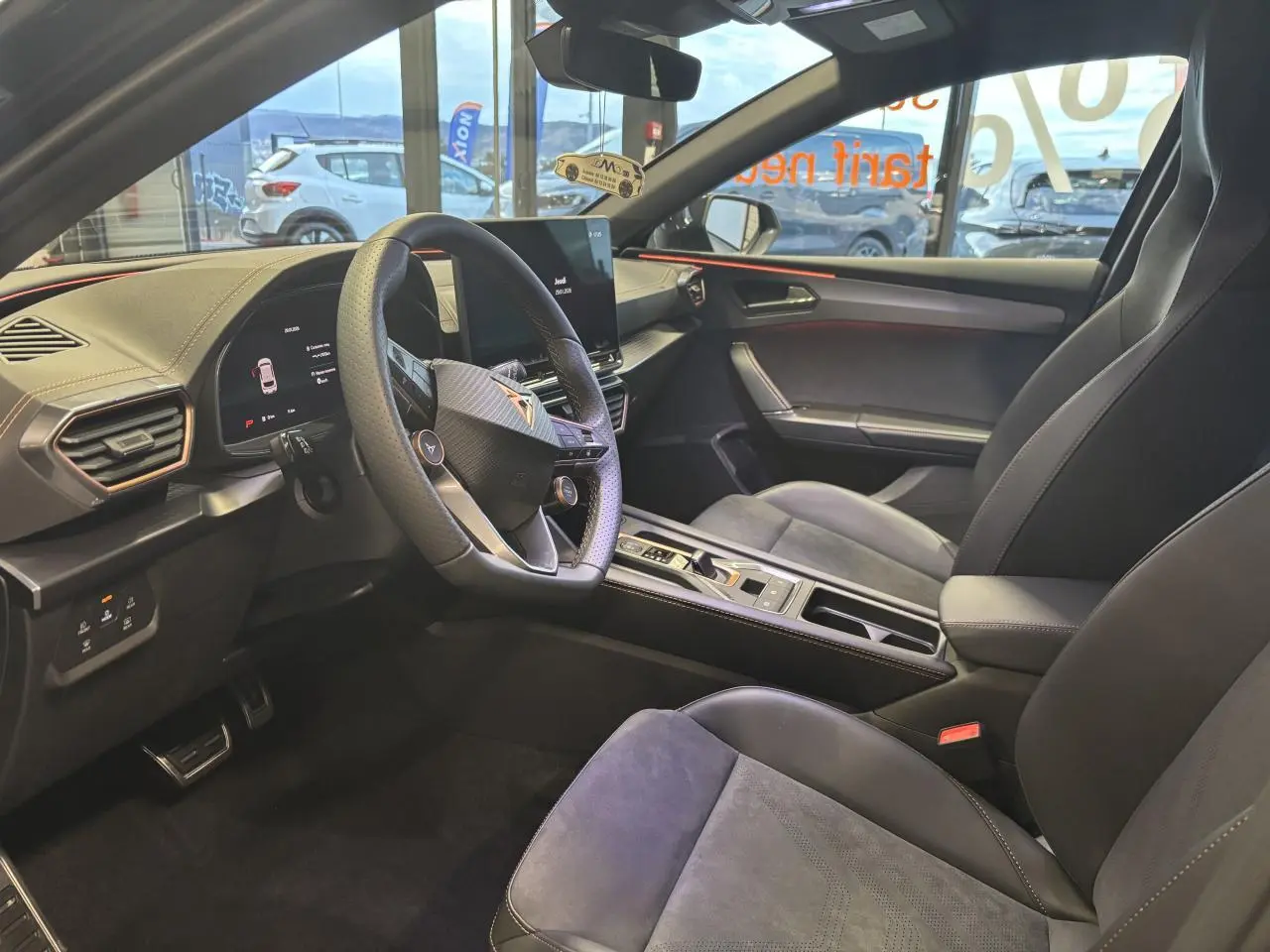 Intérieur avant droit de la CUPRA Leon noir midnight, volant cuir perforé et sièges baquets suédine avec surpiqûres cuivrées.