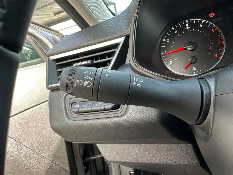 Détail du commodo d’éclairage et clignotants à gauche du volant dans une Renault Clio gris 2023 essence.