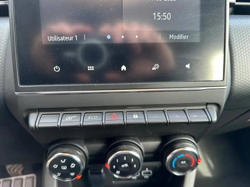 Tableau de bord de Renault Clio 2023 gris, vue rapprochée sur commandes climatisation et écran tactile central.