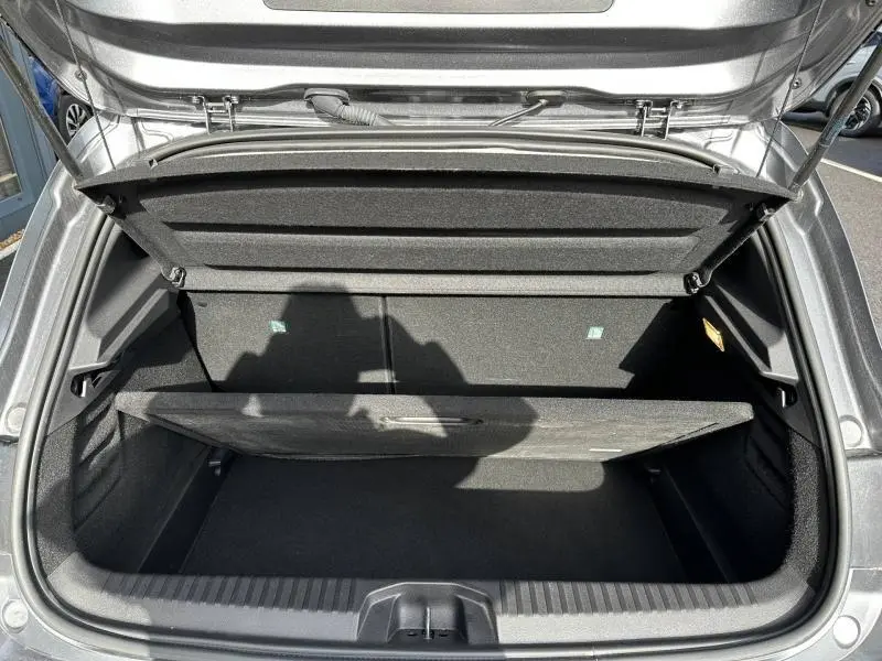 Coffre ouvert vu de dessus d'une Renault Clio gris 2023, montrant le compartiment de rangement avec cache-bagages partiellement relevé.