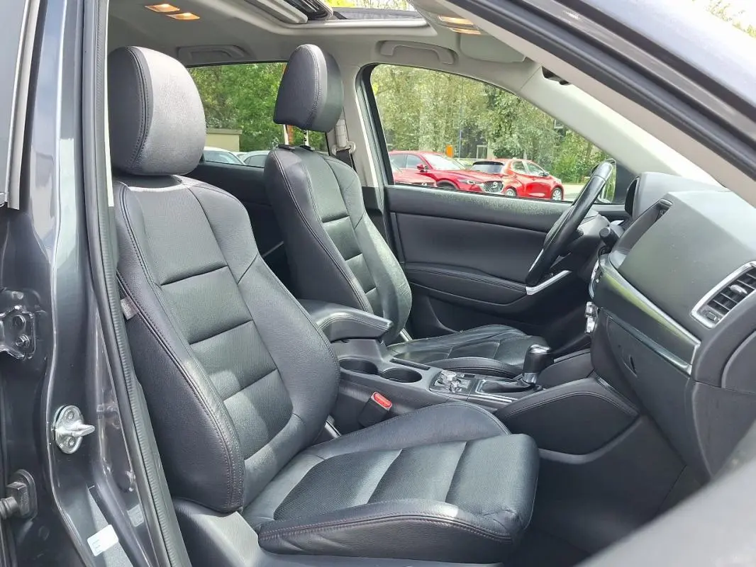 Intérieur noir cuir du Mazda CX-5 2015 vu côté conducteur avec toit ouvrant électrique et tableau de bord moderne.