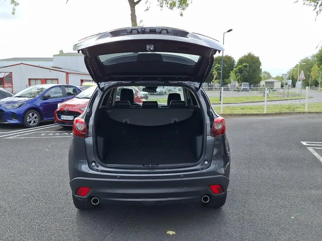 Vue arrière d'un Mazda CX-5 gris 2015 avec coffre ouvert, révélant un espace de chargement spacieux.