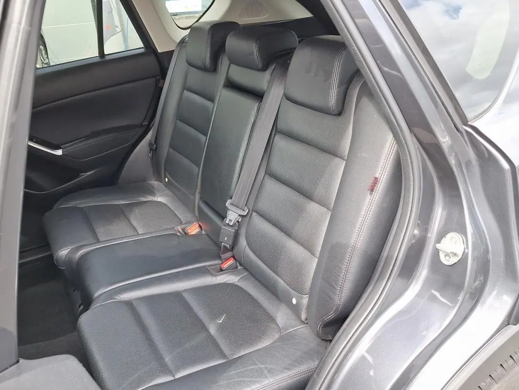 Vue intérieure côté droit sur les sièges arrière en cuir noir du Mazda CX-5 gris 2015 avec porte ouverte.