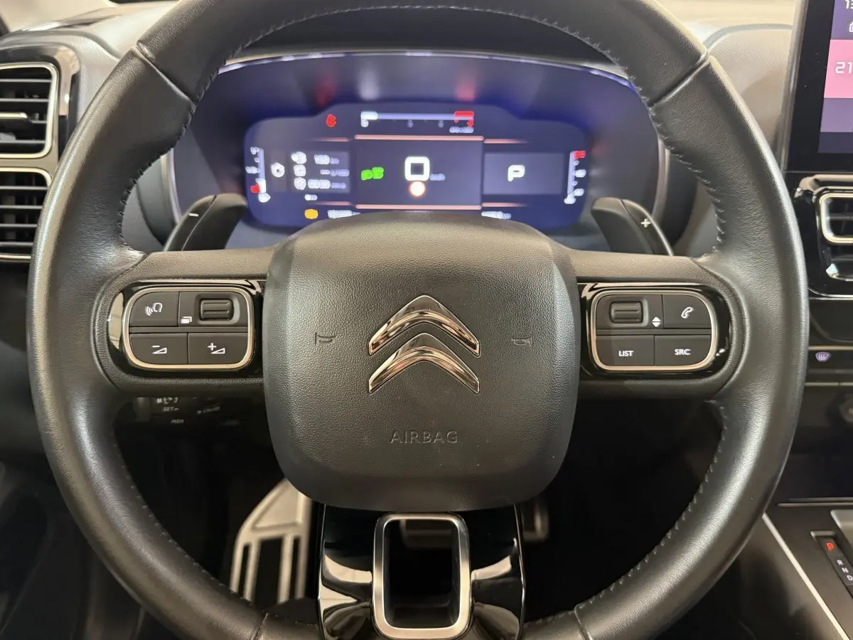 Vue rapprochée du volant cuir multifonctions de la Citroën C5 Aircross 2023 avec tableau de bord numérique lumineux.