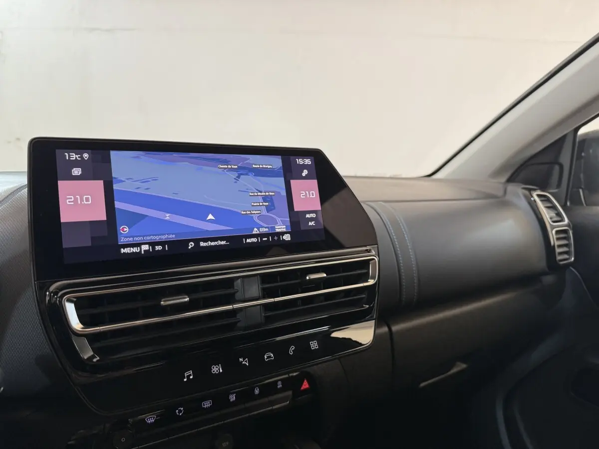 Vue intérieure du tableau de bord du Citroën C5 Aircross gris clair, avec écran tactile central affichant la navigation.