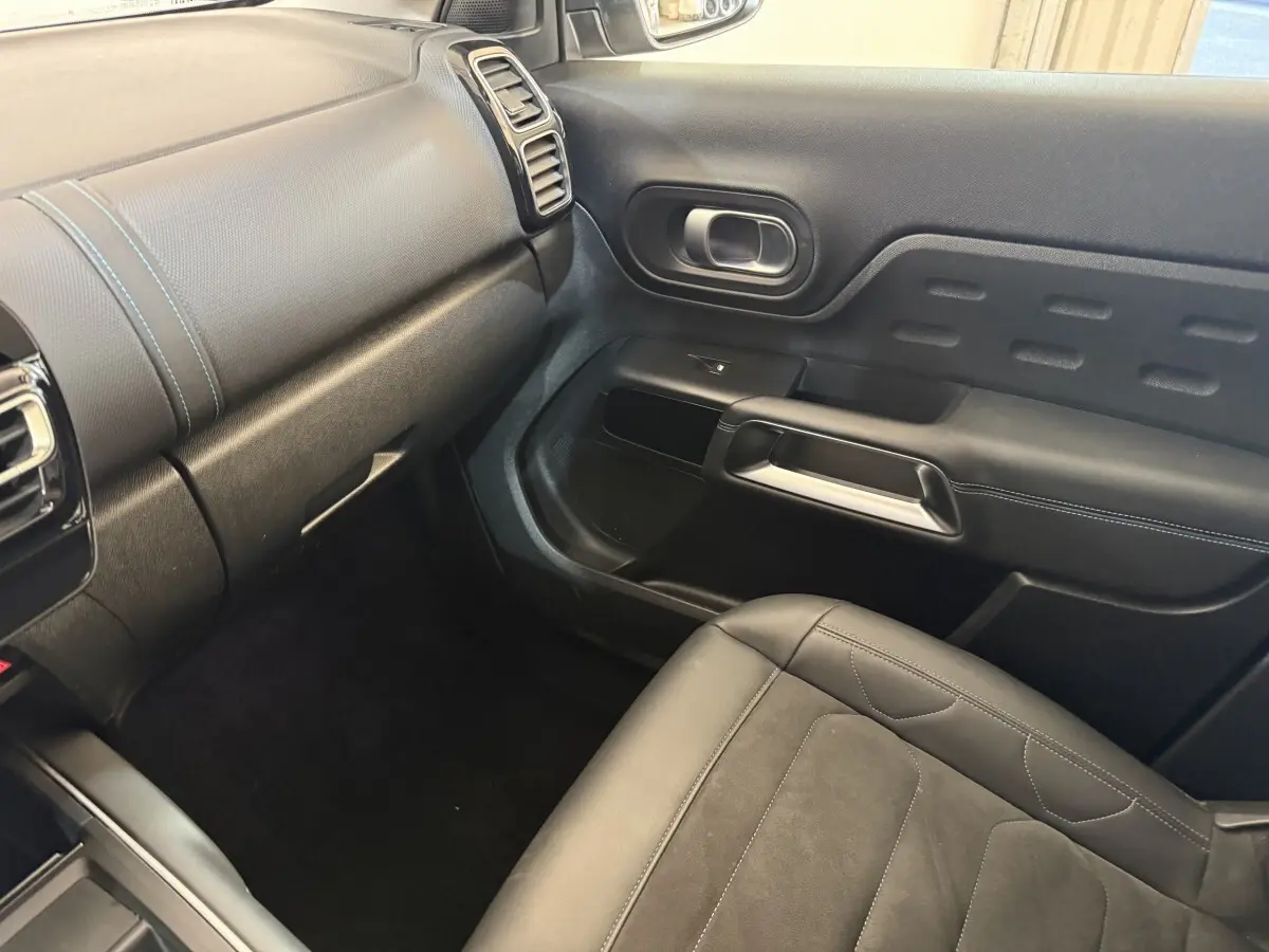 Vue intérieure côté passager avant du Citroën C5 Aircross gris clair, montrant siège et panneau de porte noirs.