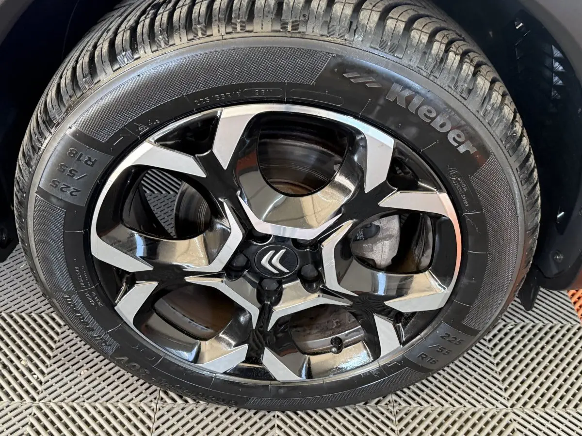 Gros plan sur la roue avant droite d'une Citroën C5 Aircross gris clair, avec pneu 225/55 R18 visible.