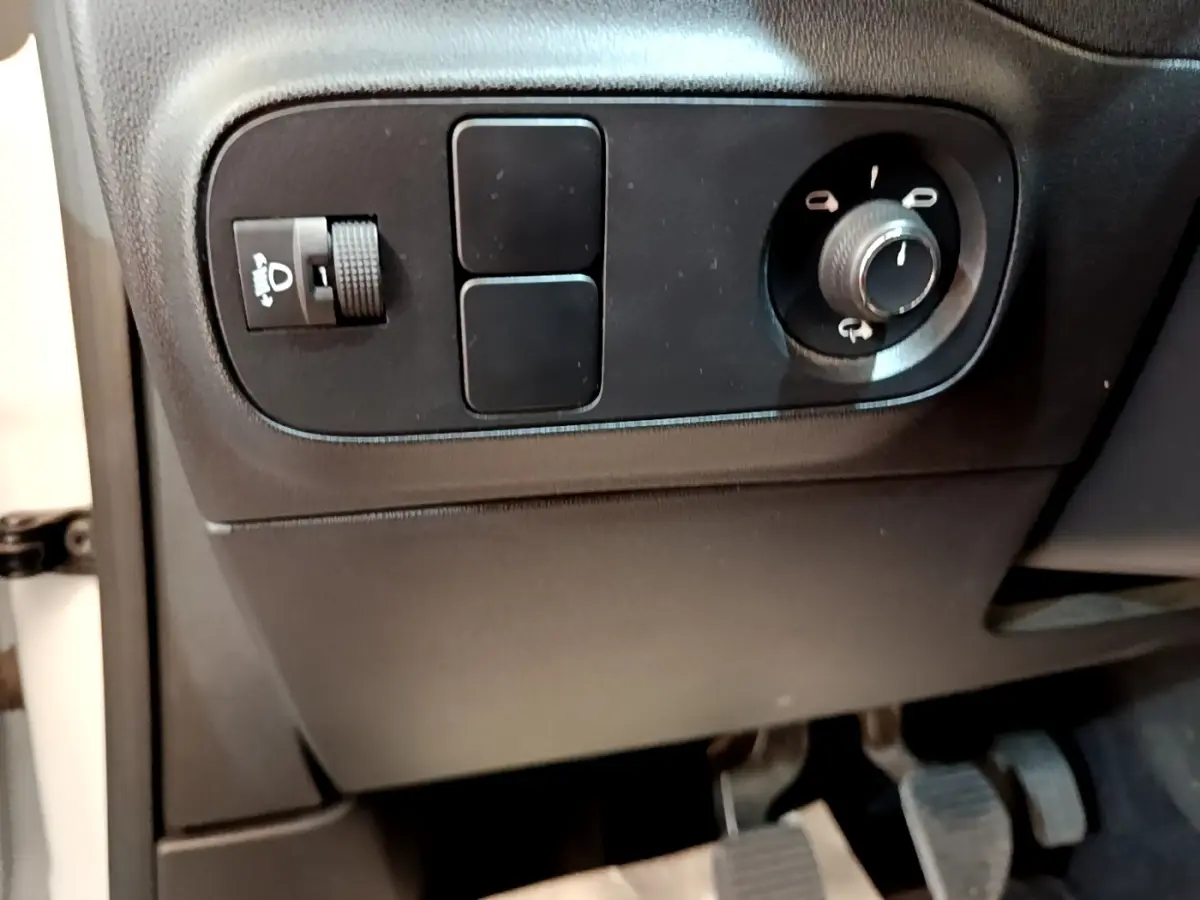 Gros plan sur les commandes d'éclairage et réglage des rétroviseurs côté conducteur d'une Citroën C3 blanche 2021.