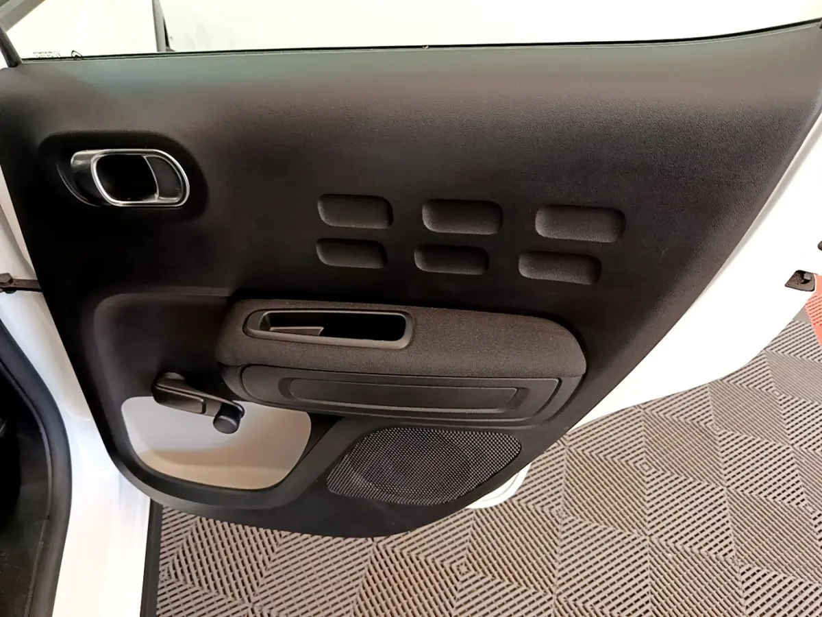 Vue rapprochée de la porte arrière gauche noire et blanche d'une Citroën C3 2021 avec poignée manuelle et haut-parleur intégré.
