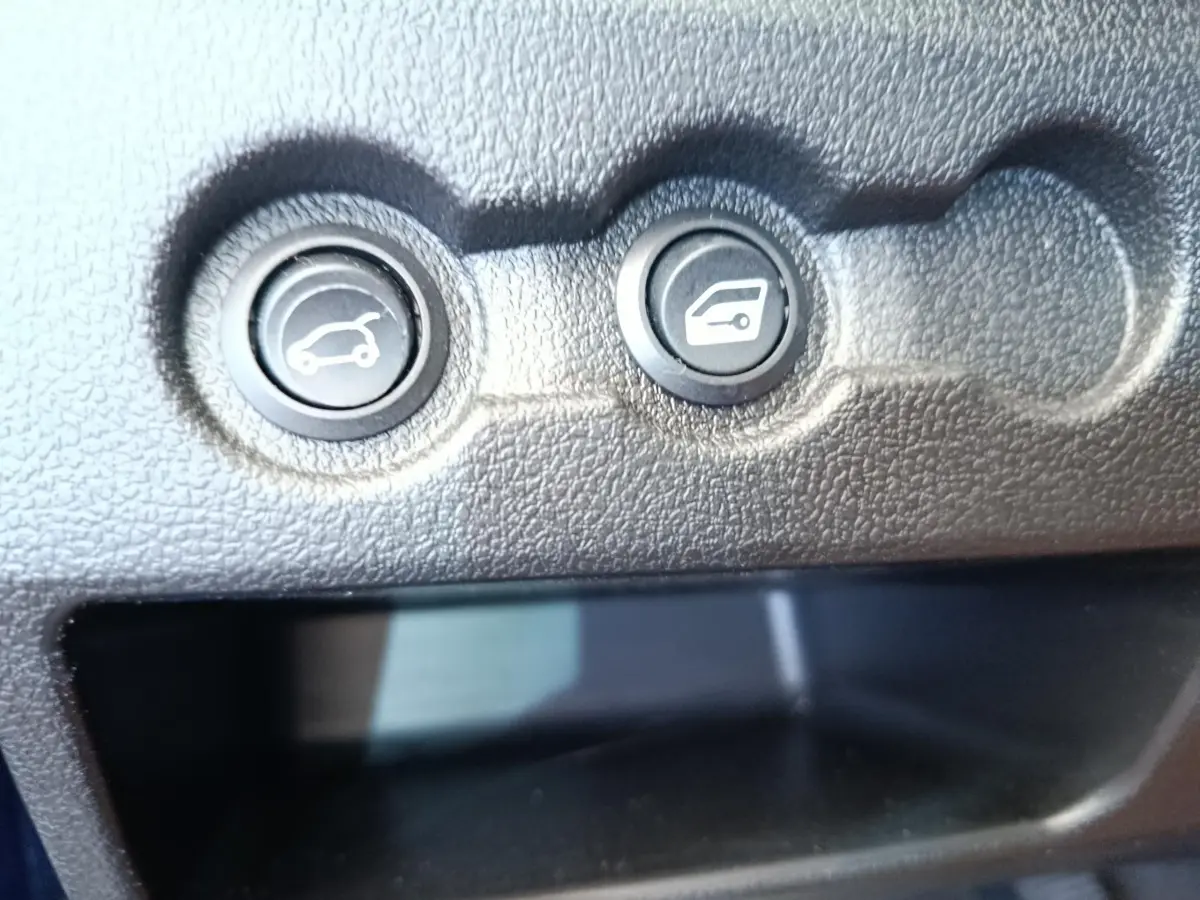 Gros plan sur les boutons d’ouverture du coffre et de la trappe à carburant dans l’habitacle de l’AIXAM AMBITION 0.5 CITY SPORT bleu.