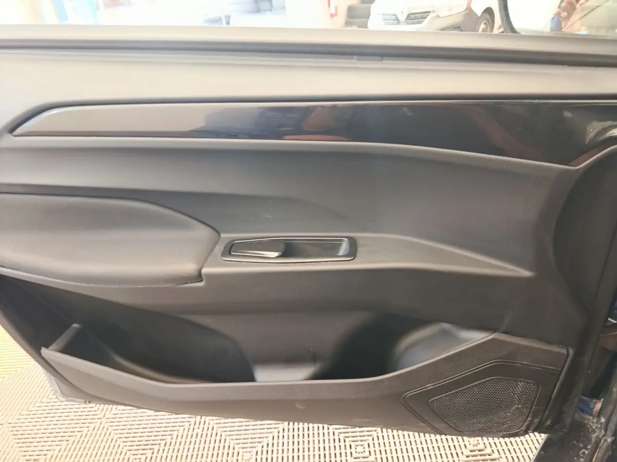 Vue rapprochée de la porte côté conducteur de l'AIXAM AMBITION 0.5 CITY SPORT 2024 en bleu, avec poignée et haut-parleur intégrés.