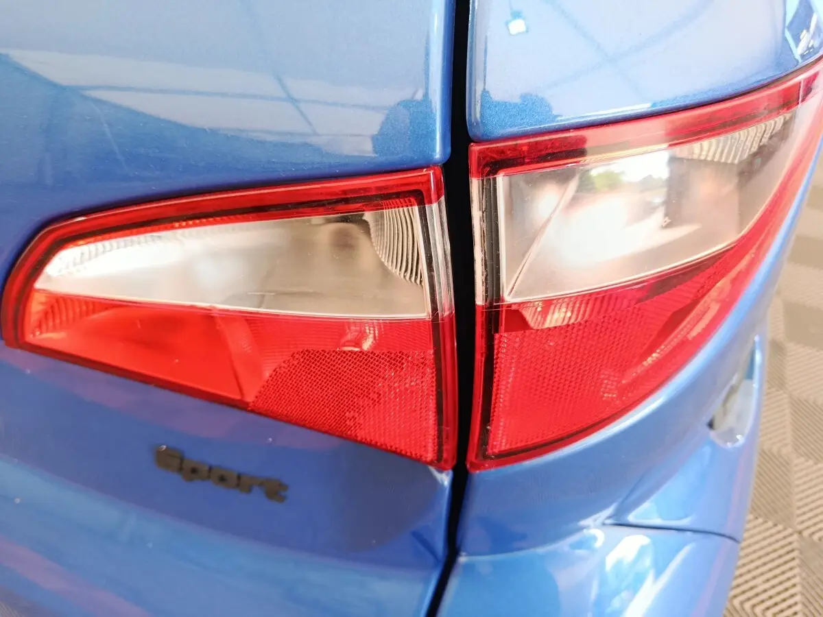 Gros plan sur les feux arrière gauche d'une Aixam Ambition 0.5 City Sport bleu 2024 avec logo Sport visible.