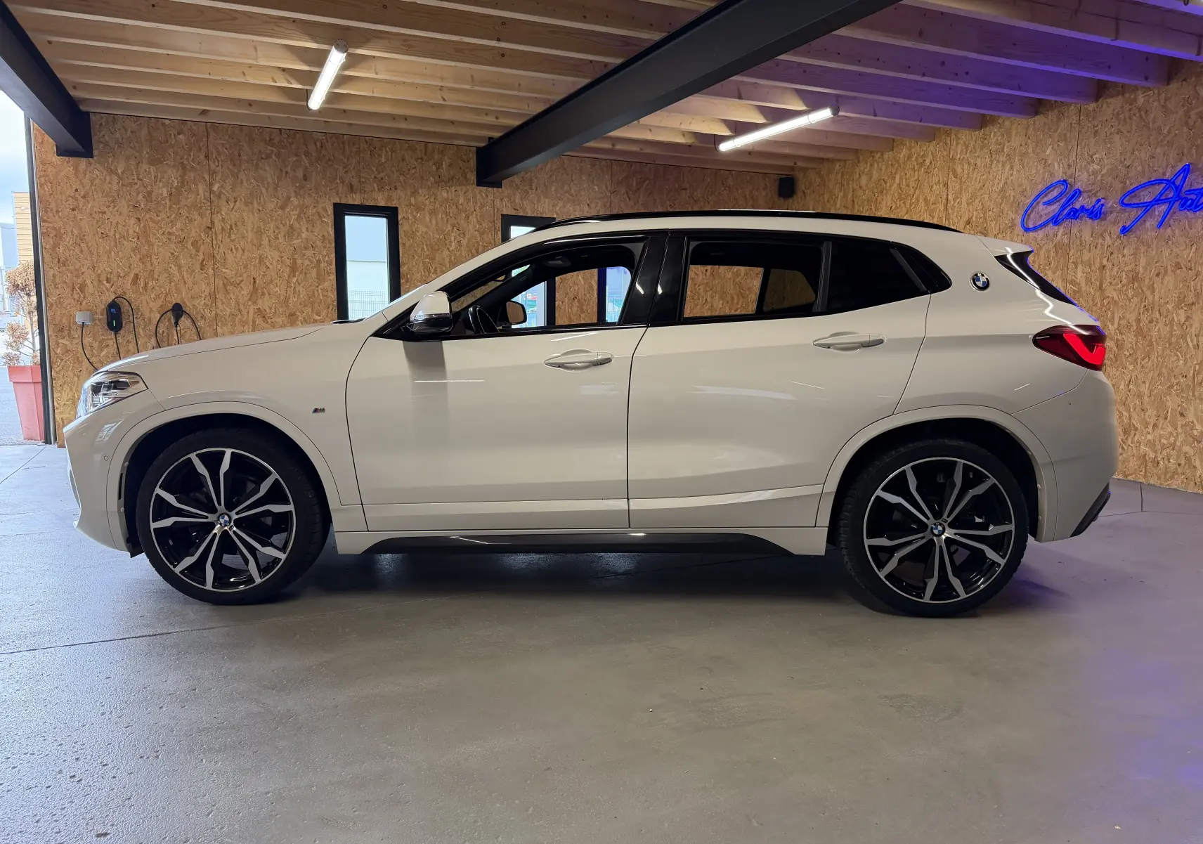 BMW X2 sDrive18d blanc vue de profil côté gauche, avec jantes alu 19'' et détails M Sport visibles.