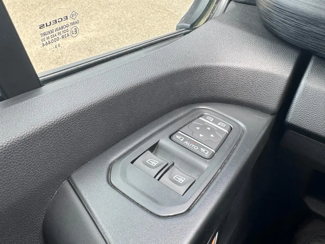 Gros plan sur les commandes électriques des vitres et rétroviseurs côté conducteur du Renault Trafic Fourgon gris foncé 2024.