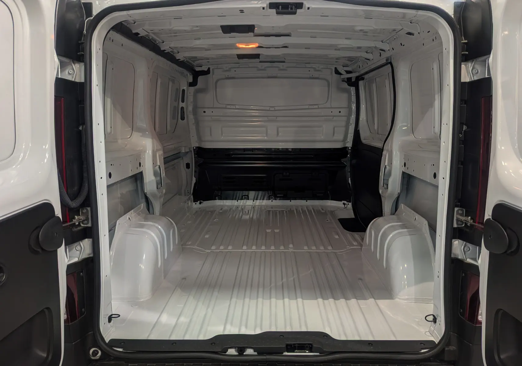 Vue arrière intérieure du Renault Trafic Fourgon blanc glacier L1H1 3T, montrant l'espace de chargement vide et la structure métallique.