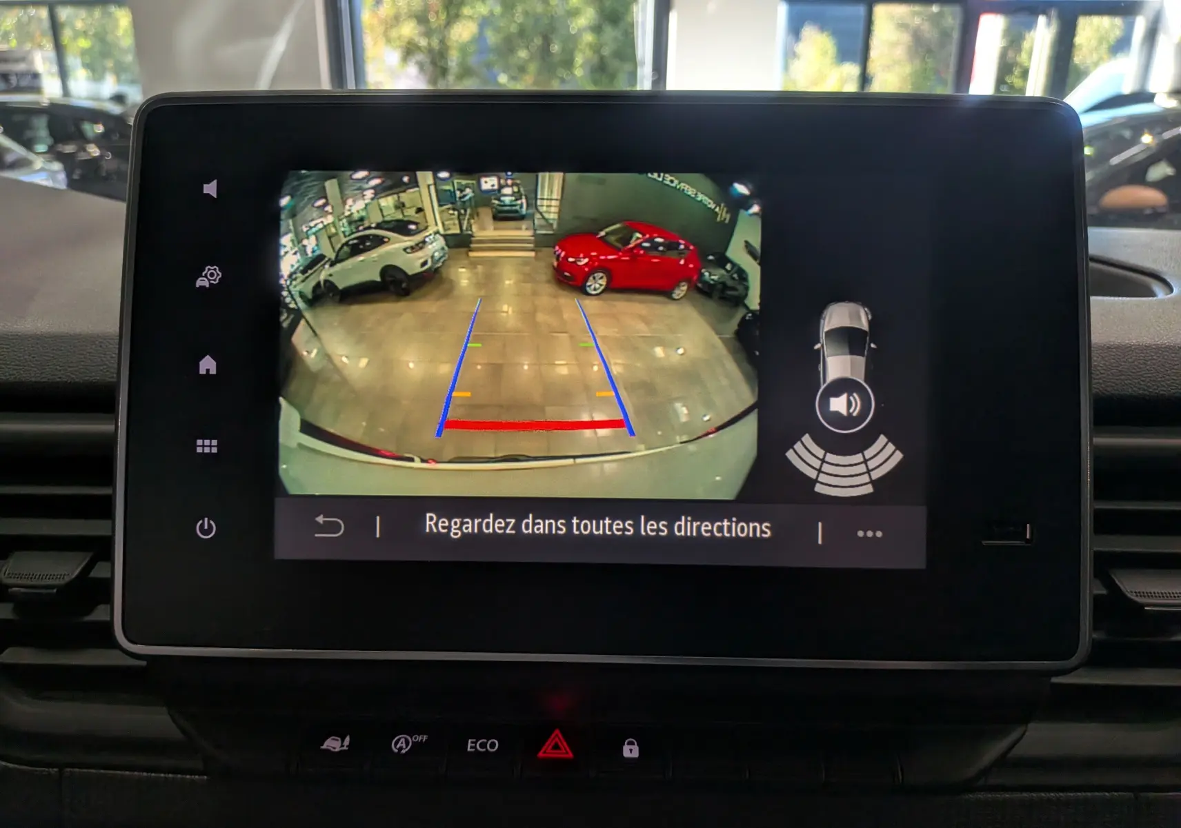 Écran multimédia montrant la caméra de recul du Renault Trafic Fourgon blanc glacier, avec lignes de guidage colorées.