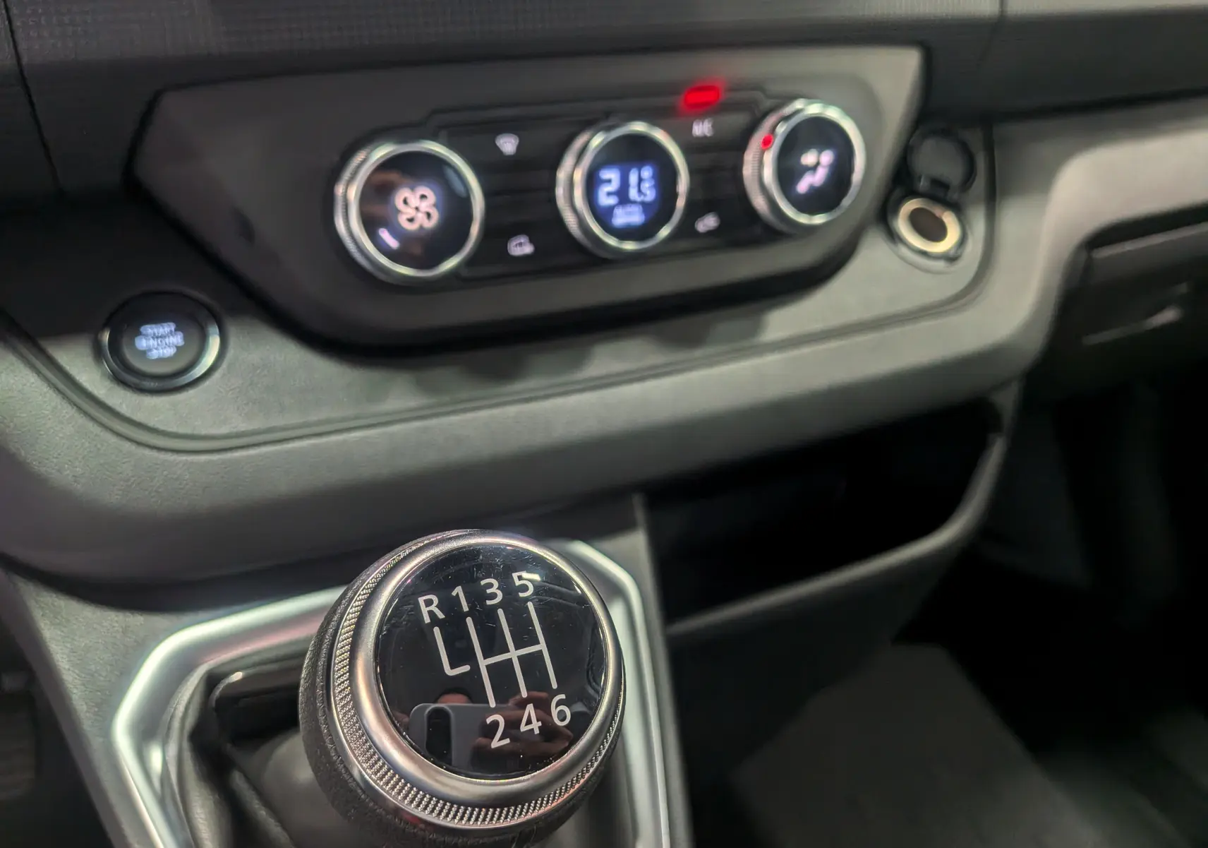 Gros plan sur la console centrale du Renault Trafic Fourgon L1H1 2025, avec levier de vitesse manuel et commandes de climatisation.