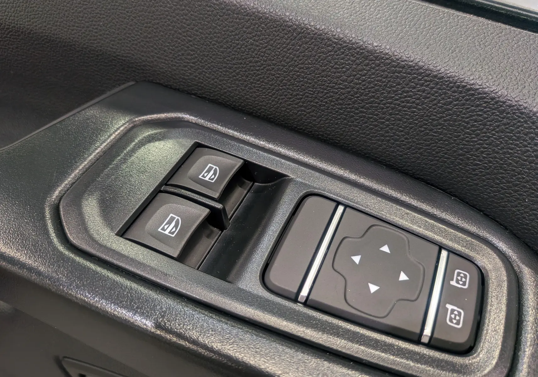 Gros plan sur les commandes électriques des vitres et rétroviseurs côté conducteur du Renault Trafic Fourgon blanc glacier 2025.