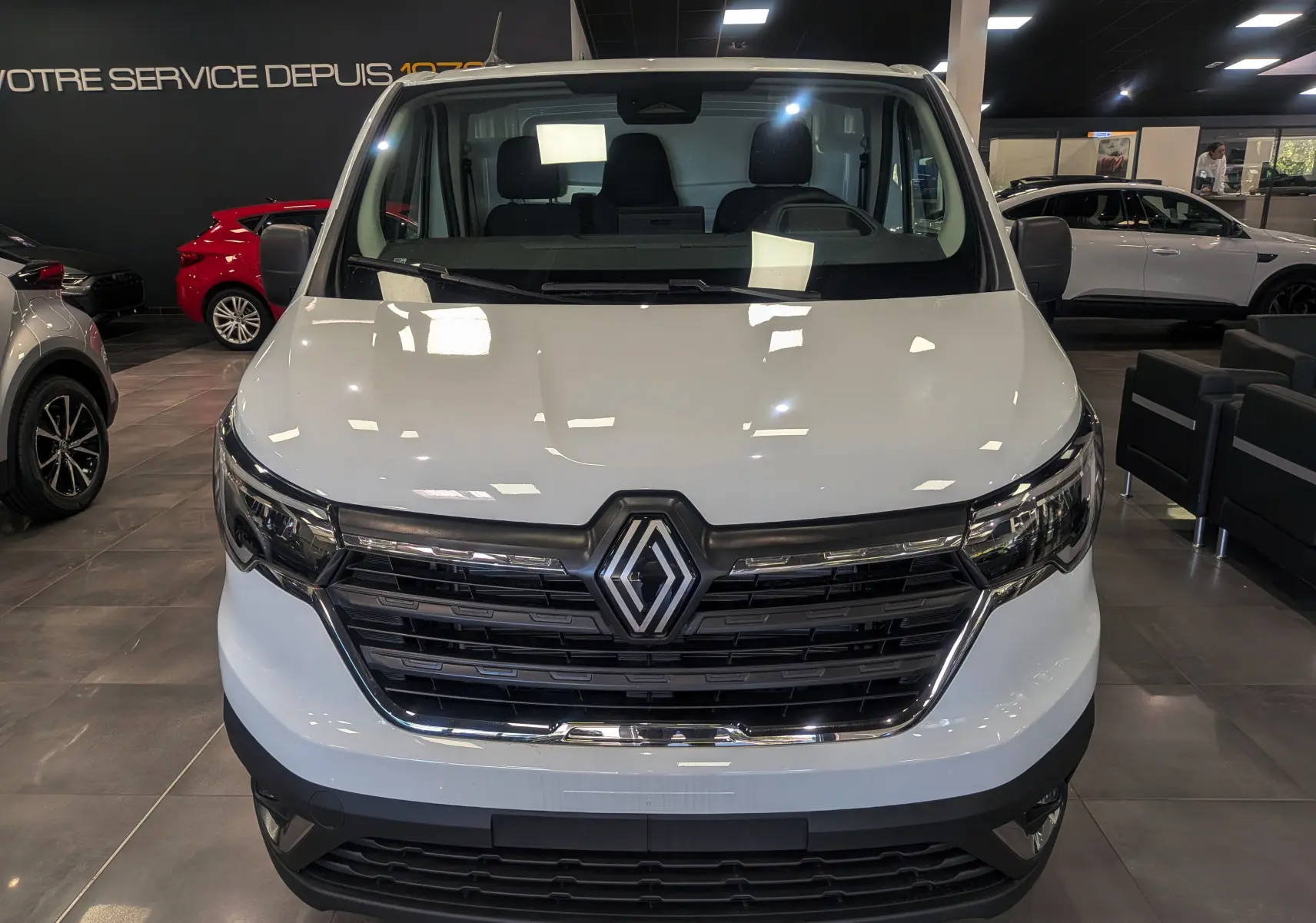 Vue frontale d'un Renault Trafic Fourgon blanc glacier 2025 avec calandre noire et logo Renault central visible.